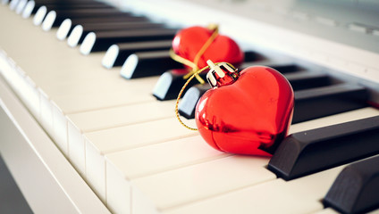 Two red glossy hearts on piano keyboard, love and vintage concept