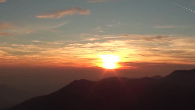 Fiery sunset from mountain pick with thin glazes in the sky evening. Fall season. Orobie alps. The summit of Mount Rena. Bergamo Italy. 