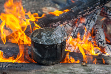 Cooking in the nature. Cauldron with ice on fire in forest.