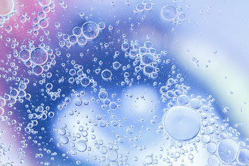 Oil drops floating in water abstract blue color background.