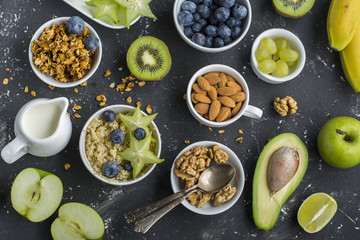 Ingredients for a healthy breakfast,avocado, quinoa bowl, carambola, green apple, banana, kiwi, nuts, oatmeal, berries fruits blueberry almonds walnuts Top view Greenery