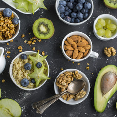 Ingredients for a healthy breakfast,avocado, quinoa bowl, carambola, green apple, banana, kiwi, nuts, oatmeal, berries fruits blueberry almonds walnuts Top view Greenery