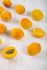 Ripe yellow apricots on a light wooden table close-up.