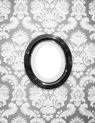 Black and white of oval wall picture frame at center on classic wallpaper