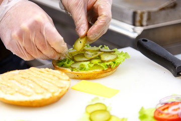 The cook prepares the hamburgers in the kitchen. Bun, veggies, P