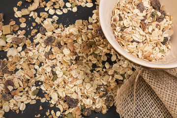 Bowl of muesli with dry fruits, on black background.
