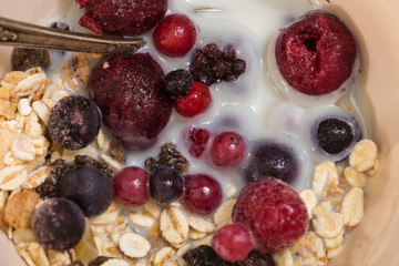 Bowl of muesli with frozen berries and plant milk closeup background