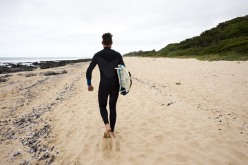 Surfer walks along beach