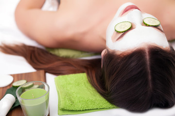 Obraz na płótnie Canvas people, beauty, spa, cosmetology and skincare concept - close up of beautiful young woman lying with closed eyes and cosmetologist applying facial mask by brush in spa