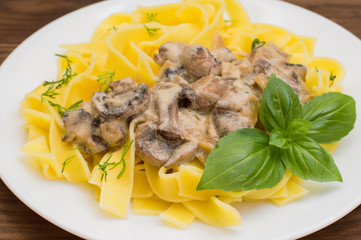 Fettuccine pasta in a creamy sauce with mushrooms on  plate   wooden table. Horizontal top view. Close-up