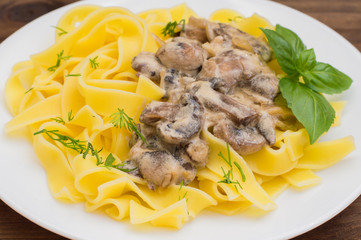 Fettuccine pasta in a creamy sauce with mushrooms on  plate   wooden table. Horizontal top view. Close-up
