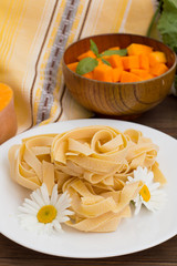 Raw fettuccine with flowers on wooden background. Italian Cuisine. Close-up