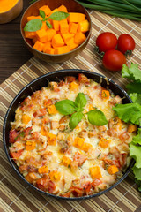 Casserole with chicken and pumpkin in a pan. Wooden rustic background. Top view. Close-up