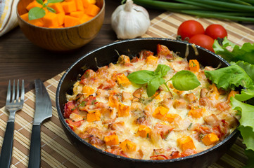 Casserole with chicken and pumpkin in a pan. Wooden rustic background. Close-up