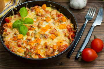 Casserole with chicken and pumpkin in a pan. Wooden rustic background. Close-up