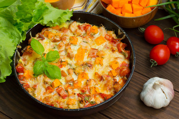 Casserole with chicken and pumpkin in a pan. Wooden rustic background. Top view. Close-up