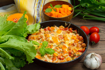 Casserole with chicken and pumpkin in a pan. Wooden rustic background. Top view. Close-up