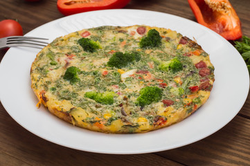 Spanish tortilla on a white plate. Restaurant supply. Wooden rustic table. Top view