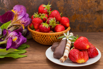 Strawberries with chocolate on a background of flowers. Wooden table. Close-up