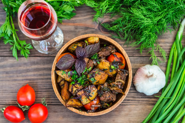 Roasted meat with potatoes, ojaxuri, hot in Georgian and red wine on a wooden table. Top view. Close-up