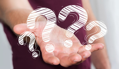 Businessman holding hand drawn question marks in his hand