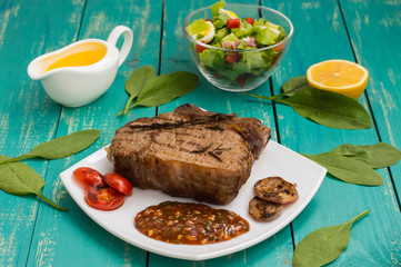 Beef steak medium rare on the grill with barbecue sauce. wood background