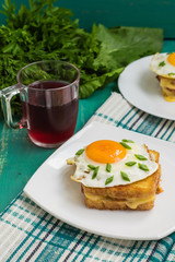 Croque-Madame, a French sandwich with greens and berry juice for breakfast. Wooden table. Top view. Close-up