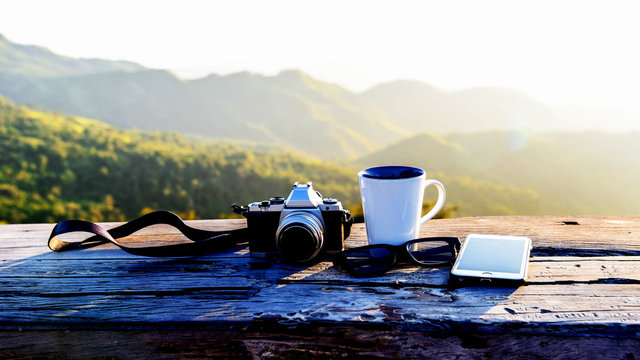 set of cameras, smart phone and glasses on wooden desk.