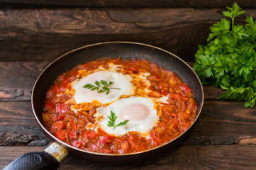 Shakshuka in a frying pan. Traditional Jewish dish. Wooden table. Close-up