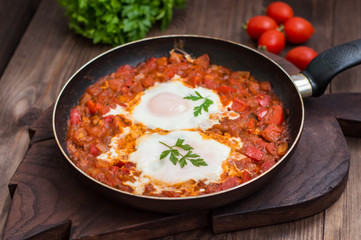 Shakshuka in a frying pan. Traditional Jewish dish. Wooden table. Close-up