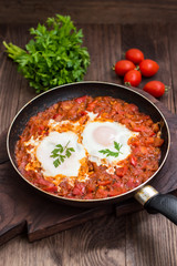 Shakshuka in a frying pan. Traditional Jewish dish. Wooden table. Close-up