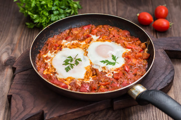 Shakshuka in a frying pan. Traditional Jewish dish. Wooden table. Close-up