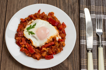 Shakshuka on a white plate. Traditional Jewish dish. Wooden table. Close-up