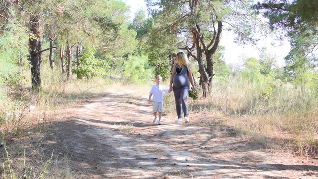 Pregnant mother and son walking through the woods