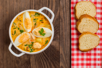 Cream soup with smoked chicken and eggs on a wooden table. Top view. Close-up