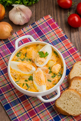Cream soup with smoked chicken and eggs on a wooden table. Top view. Close-up