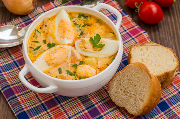 Cream soup with smoked chicken and eggs on a wooden table. Top view. Close-up