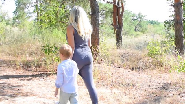 Pregnant Mother And Son Walking Through The Woods