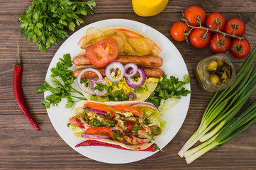 Ingredients for a picnic consisting of vegetables and sausages grilled on wooden rustic background, top view. Close-up