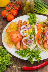 Ingredients for a picnic consisting of vegetables and sausages grilled on wooden rustic background, top view. Close-up