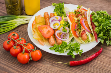 Ingredients for a picnic consisting of vegetables and sausages grilled on wooden rustic background, top view. Close-up