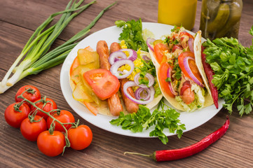 Ingredients for a picnic consisting of vegetables and sausages grilled on wooden rustic background, top view. Close-up