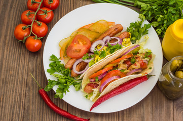 Ingredients for a picnic consisting of vegetables and sausages grilled on wooden rustic background, top view. Close-up