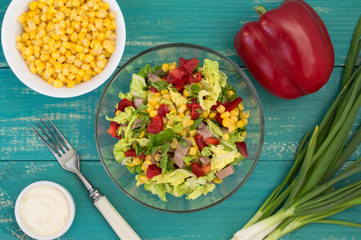 Salad from beef tongue, Chinese cabbage, peppers, corn, parsley and basil. Wooden background. Top view. Close-up