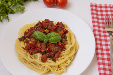 Italian pasta with tomatoes, capsicum and beef tongue on a white table