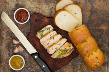 Garlic bread with fried chicken, greens and sauce on a wooden background. Top view. Close-up