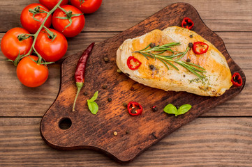 Chicken fillet, fried on the grill and laid out  a wooden board with spices  herbs.  table. Top view