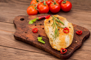 Chicken fillet, fried on the grill and laid out  a wooden board with spices  herbs.  table. Top view