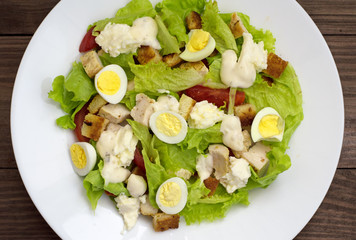 Salad with grilled chicken, lettuce and mozzarella cheese on a wooden background. Top view. Close-up