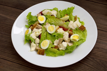 Salad with grilled chicken, lettuce and mozzarella cheese on a wooden background. Top view. Close-up